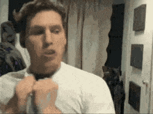 a man in a white shirt adjusts his tie