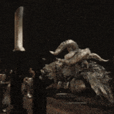a statue with horns is laying on a table next to a candle