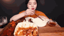 a woman is eating a meal with chopsticks and a bowl of rice