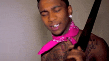 a shirtless man wearing a pink bandana is holding a large knife .