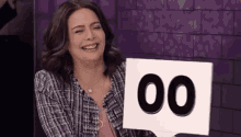 a woman is laughing while holding a sign that says 00 .