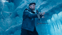 a man in a black jacket is holding a hammer in front of a blue background that says tom3/2005