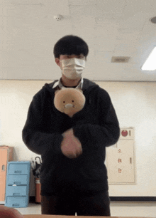 a man wearing a mask holds a stuffed animal