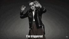 a man wearing sunglasses and a leather jacket says " i 'm triggered "