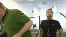 a man in a green shirt and a man in a black shirt are standing next to each other on stairs .