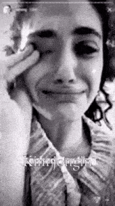 a black and white photo of a woman crying while holding her hand to her face .