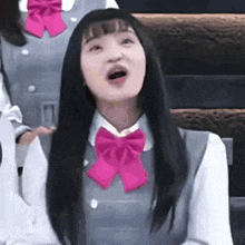 a girl in a school uniform with a pink bow tie .