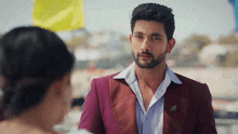 a man with a beard is wearing a maroon suit and a white shirt