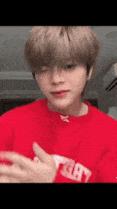 a young boy wearing a red sweater is making a funny face .