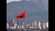 a red flag is waving in the wind in front of a city