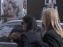 two women are standing in front of a car that says csi on the window