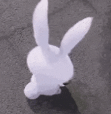 a white stuffed bunny rabbit is standing on a concrete surface .