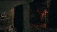 a man with blood on his face is looking out of a doorway