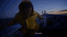 a man in a yellow jacket is riding a boat in the ocean ..