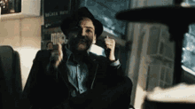 a man wearing a hat is sitting in a chair smoking a cigarette ..