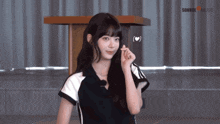 a girl in a black and white shirt is standing in front of a table that says source music