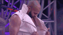 a man is taking off his white vest on a stage .
