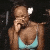 a woman with a flower in her hair is covering her eyes with her hand .