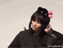 a person wearing a hello kitty hat is making a heart shape with their hands