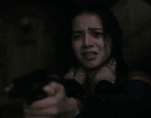 a woman is crying while holding a gun in her hand in a dark room .