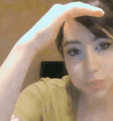 a woman is holding her hand to her forehead while looking at the camera .