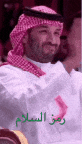 a man in a white shirt and a red and white head scarf is smiling .