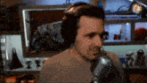 a man wearing headphones stands in front of a microphone in a room