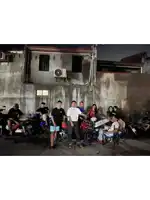 a group of people standing in front of a wall with motorcycles