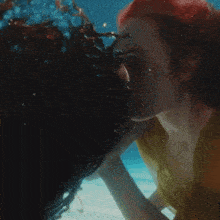 a woman in a yellow shirt is kissing another woman under water