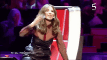 a woman in a black dress is dancing on a stage with the number 5 in the corner