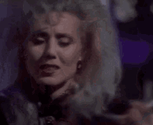 a close up of a woman 's face with a purple background and blood on her face .