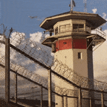 a prison tower with barbed wire around it