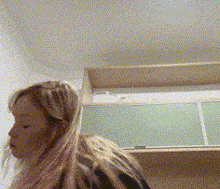 a woman with long blonde hair is standing in front of a shelf