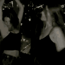 two women are standing next to each other in the dark .