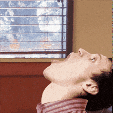 a man looks up at a window with blinds on it