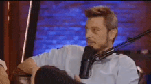 a man is sitting in front of a microphone talking into it .