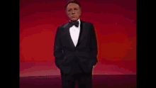 a man in a tuxedo is standing with his hands in his pockets
