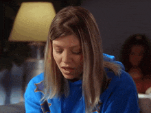 a woman in a blue sweatshirt with a star on it looks down
