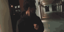 a man walking down a hallway at night with a backpack