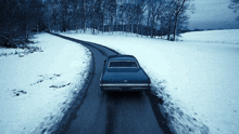a car is driving down a snowy road with a license plate that says ' cadillac ' on it