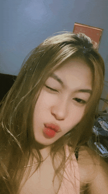 a woman with long blonde hair is making a funny face with her eyes closed