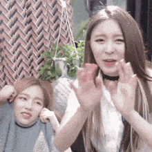 two women are sitting next to each other and one is wearing a choker around her neck