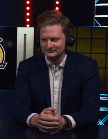 a man in a suit and headphones is sitting at a table and says no