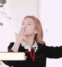 a woman blowing a kiss while wearing a black dress and a white collar