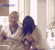 two women are laughing and one has a shirt that says philippines