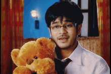 a man wearing glasses holds a teddy bear