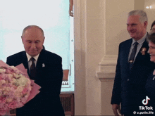 a man in a suit is holding a bouquet of flowers