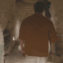 a man in an orange shirt is walking through a jungle with the words locasporponcho on the bottom right