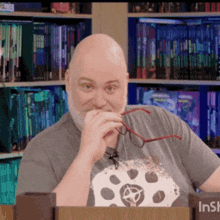 a bald man with glasses and a beard is sitting in front of a sign that says ' insh '
