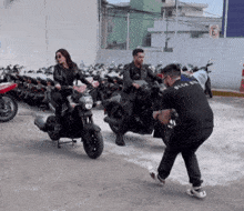 a man in a black shirt that says black on it is taking a picture of two people on motorcycles